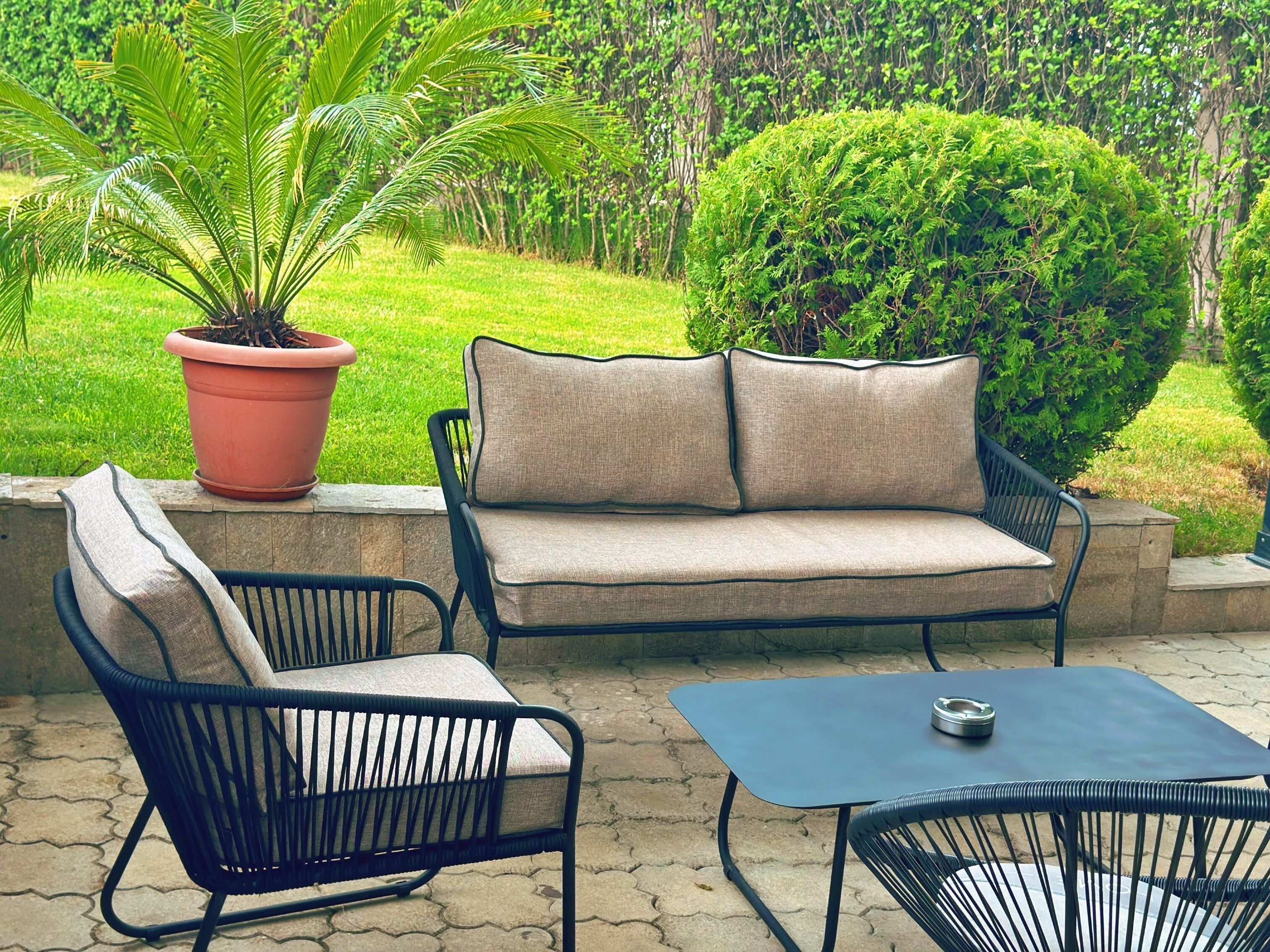 An outdoor patio with a sofa, two chairs, and a table.