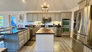 A modern kitchen with light wood cabinets, stainless steel appliances, and a central island.