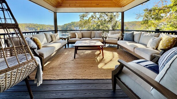 A covered outdoor seating area with a wooden ceiling, cushioned sofas, and a woven rug.