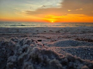 En strand med solnedgang over horisonten.