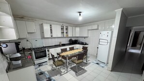A kitchen with white cabinets, a stove, a refrigerator, and a dining table with chairs.