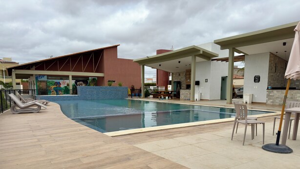 A swimming pool area with lounge chairs, a covered seating area, and a mural on the building.