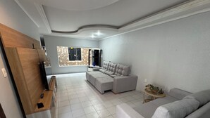 A spacious living area with a grey sofa, a sectional sofa, and a TV stand.