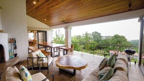Un amplio patio exterior con techo de madera, una mesa de comedor y un sofá.