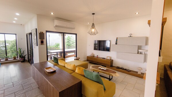 A modern living room with a wooden coffee table, yellow sofa, and a TV mounted on the wall.