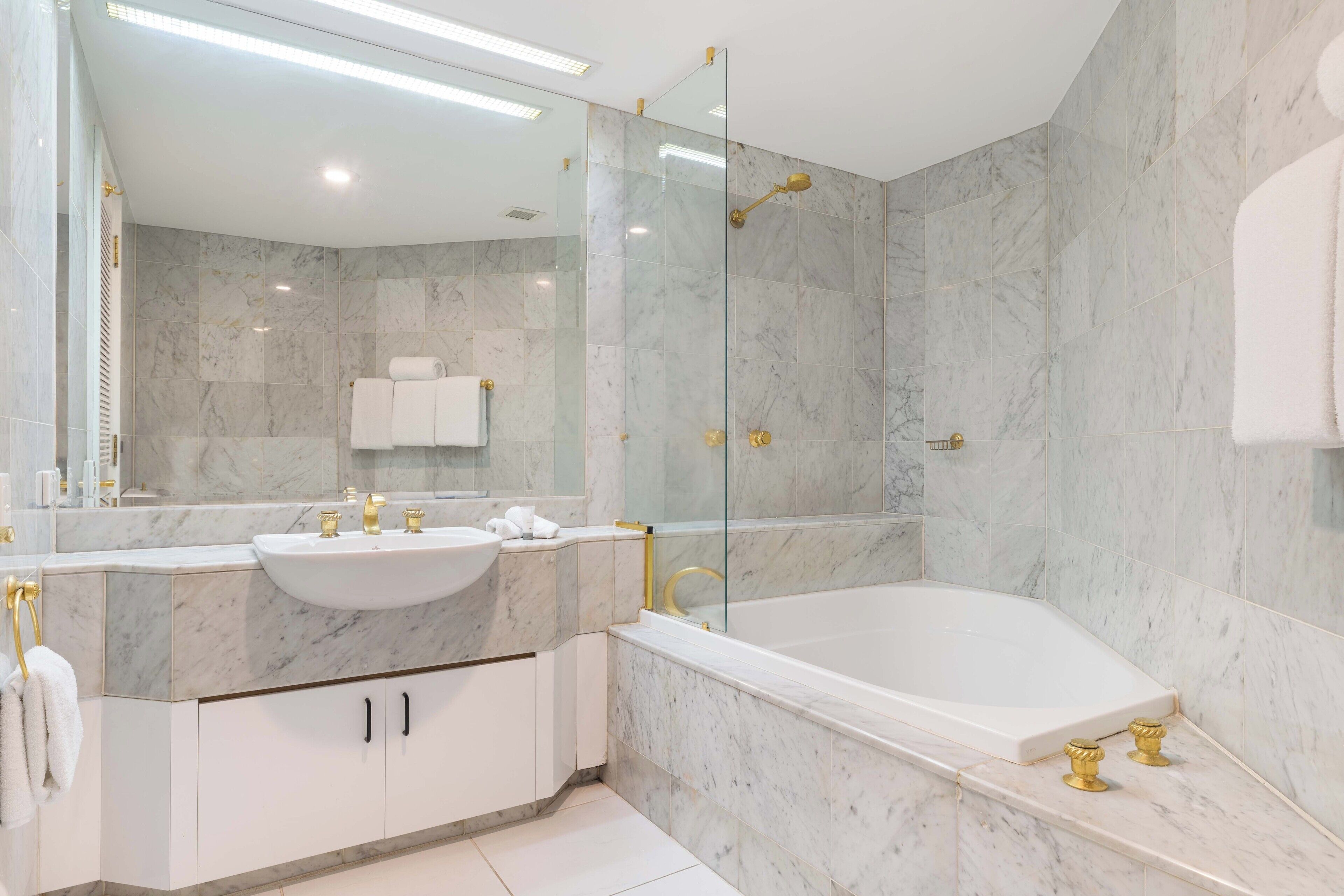 Ein modernes Badezimmer mit Marmorwaschbecken, einer Badewanne und einer gläsernen Duschkabine.