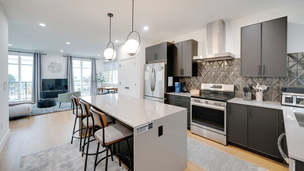 A modern kitchen with a central island, bar stools, a refrigerator, oven, and a microwave. - Modern West Seattle Home with View, 3bed, 2.5bath, AC, 2Parking (Seattle)