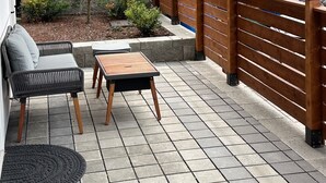 A covered patio area with a wooden fence, a small tree, and outdoor furniture. - Modern West Seattle Home with View, 3bed, 2.5bath, AC, 2Parking (Seattle)