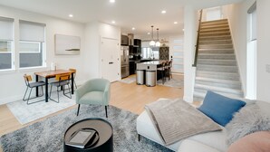 A modern apartment with a dining area, kitchen, and staircase. - Modern West Seattle Home with View, 3bed, 2.5bath, AC, 2Parking (Seattle)
