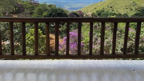 A balcony with a view of a green landscape and distant hills under a clear sky.