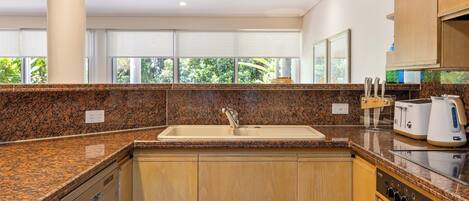 A modern kitchen with granite countertops, wooden cabinets, a built-in dishwasher, and a toaster.