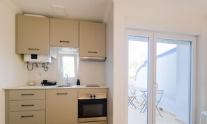 Une cuisine moderne avec des armoires de couleur beige, un four encastré et une fenêtre.
