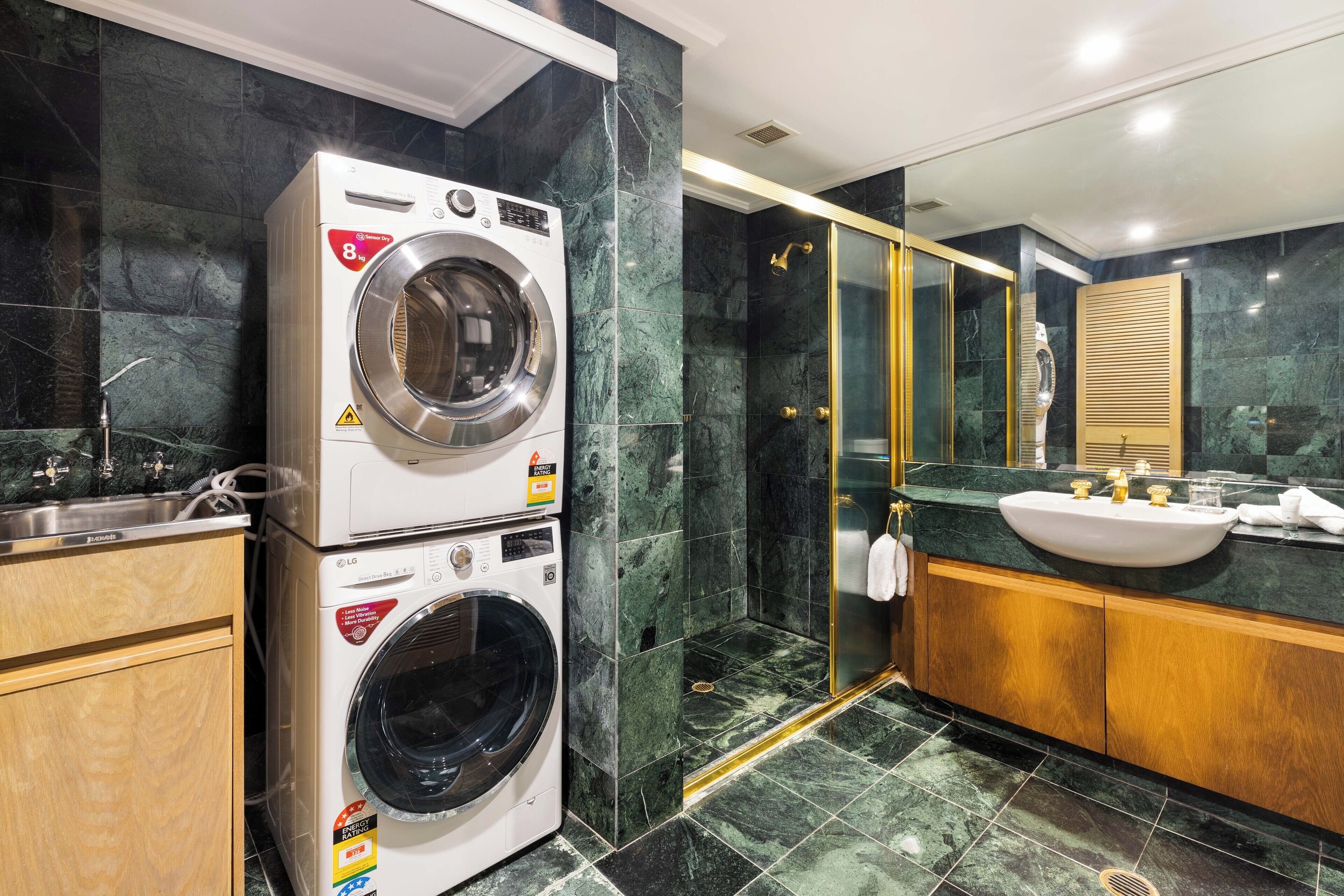 A modern bathroom with a stacked washer and dryer, a glass-enclosed shower, and a vanity with a sink.