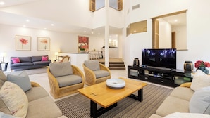 Un salón amplio con un sofá, dos sillones, una mesa de centro y un televisor.