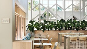 A modern restaurant interior with high ceilings, large windows, and a variety of seating arrangements including tables and benches.