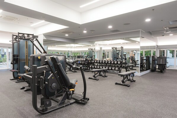 A modern gym with various exercise equipment, including weight machines and free weights.