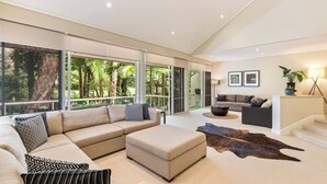 A modern living room with a large sectional sofa, ottoman, and a leather rug.