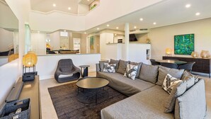 Una sala de estar moderna con un sofá seccional, una mesa de centro redonda y una zona de comedor con una mesa y sillas.