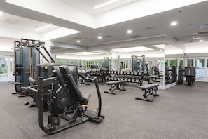 Een moderne sportschool met diverse fitnessapparaten, waaronder krachtapparaten en losse gewichten.