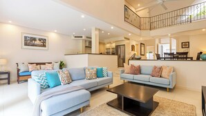 A spacious living area with two light blue sofas, a coffee table, and a staircase leading to an upper level.