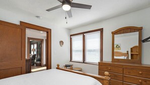 A bedroom with a bed, wooden dresser, and a ceiling fan.
