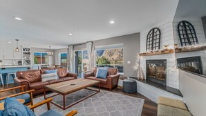 A spacious living area with leather sofas, a wooden coffee table, and a fireplace.
