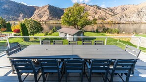 A dining area with a table and chairs overlooking a lake and mountains.