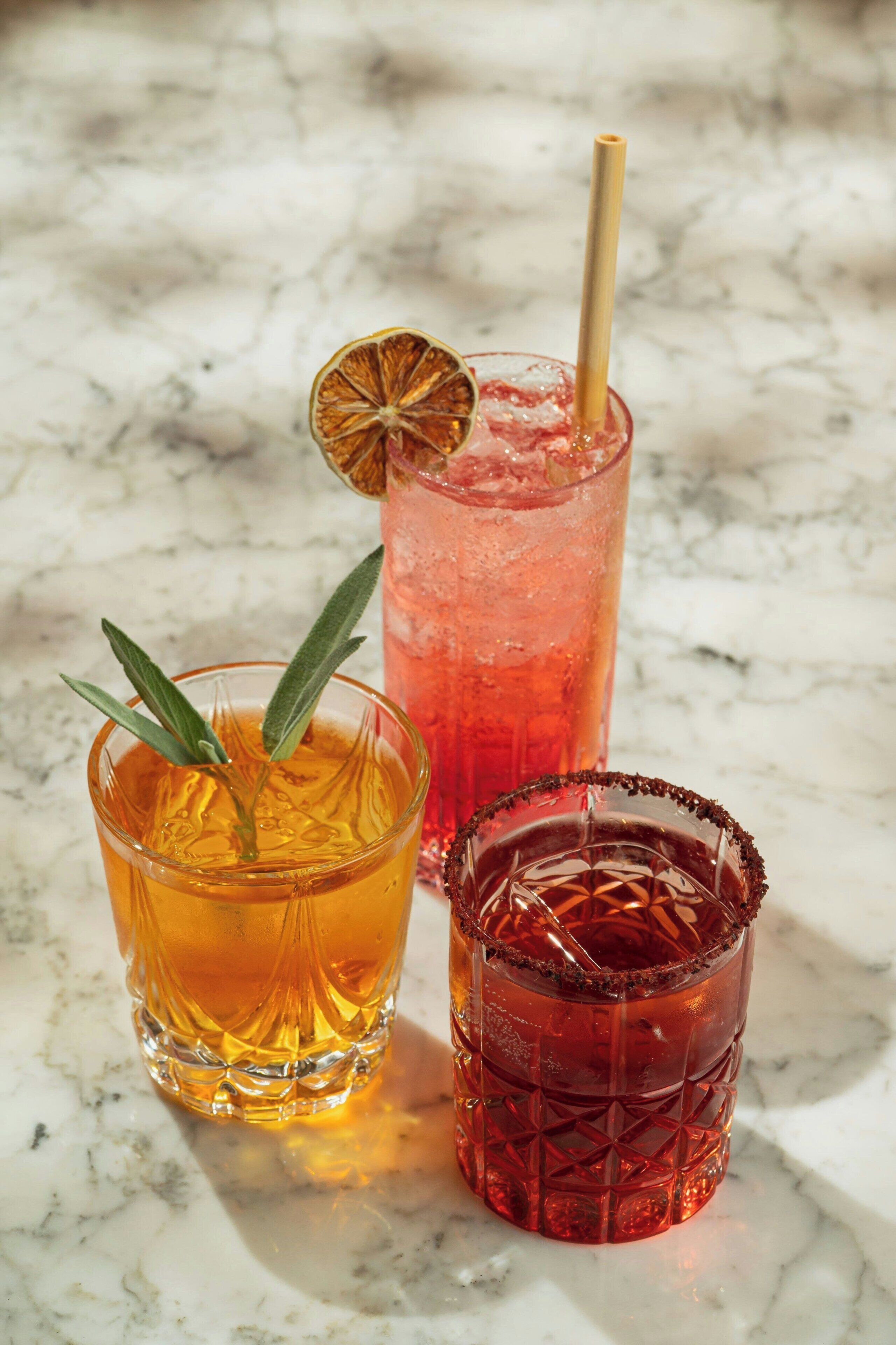 Three glasses of beverages on a marble surface.