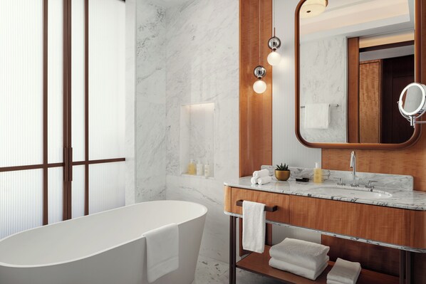A modern bathroom with a freestanding bathtub, a wooden vanity with a mirror, and marble walls. - JW Marriott Hotel Tashkent (Tashkent)