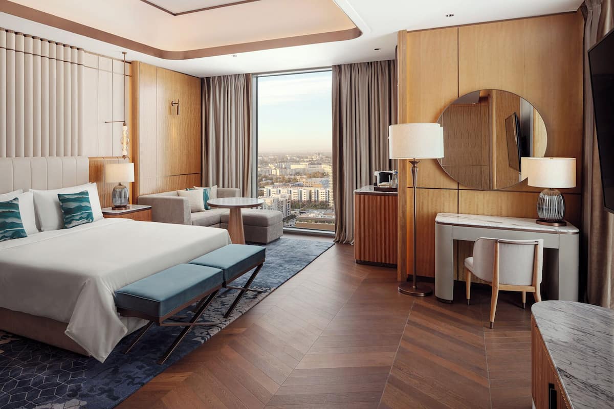 Una habitación de hotel moderna con una cama grande, un escritorio y vistas a la ciudad.
