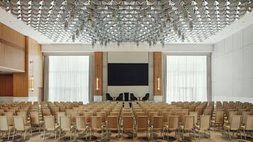 A conference room with rows of chairs, a large screen, and a patterned carpet.