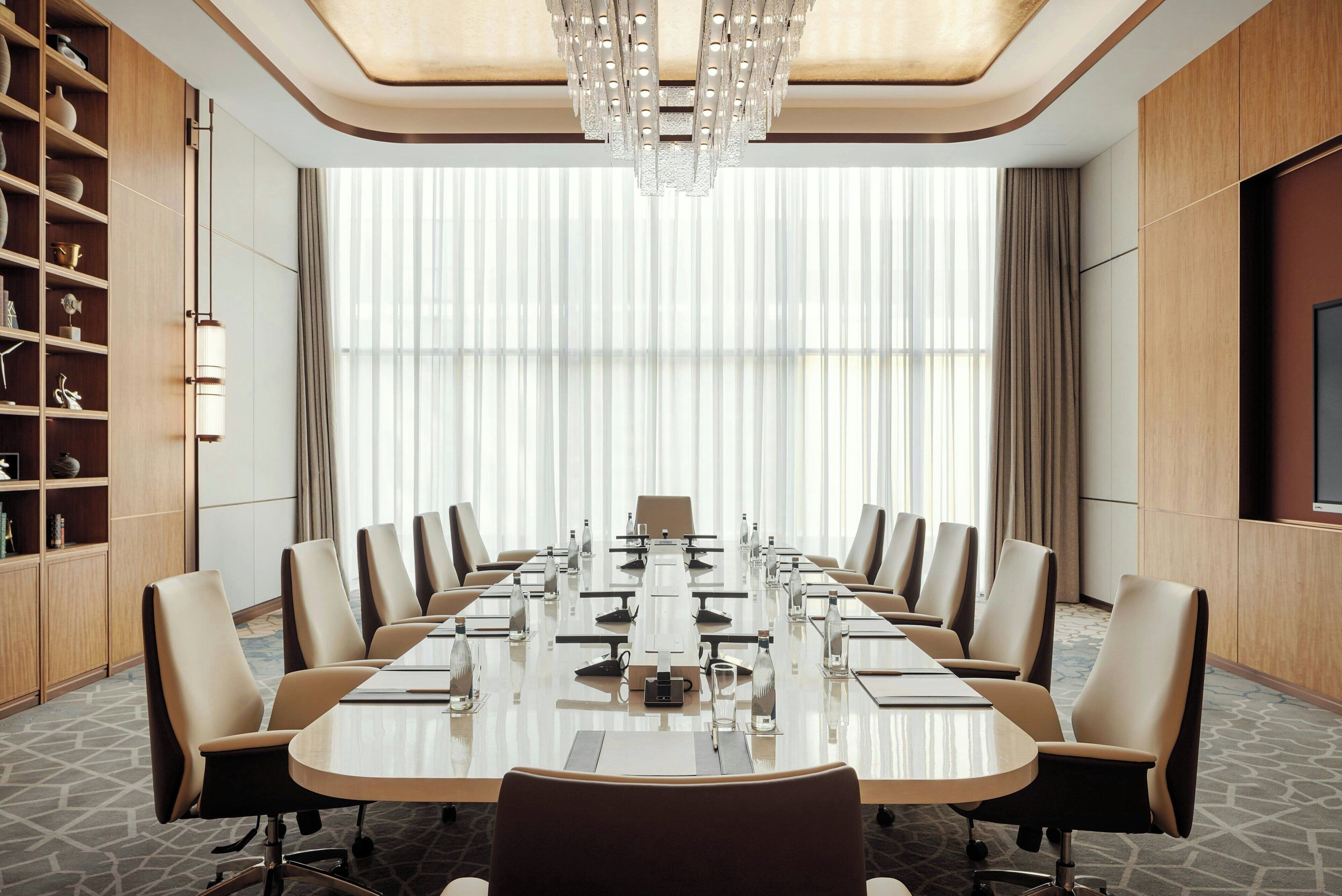 A conference room with a long table, chairs, and a chandelier.