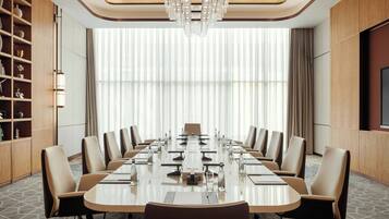 A conference room with a long table, chairs, and a chandelier.