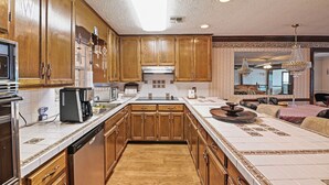 Un'ampia cucina con mobili in legno, un'isola centrale e un'area da pranzo con un lampadario.