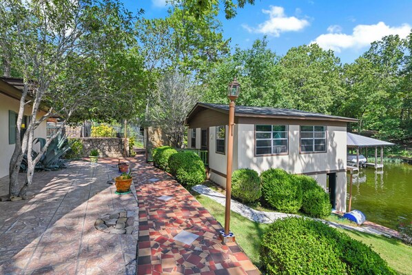 A house with a tiled patio, a pond, and surrounding greenery. - The Jordan View (Titus)