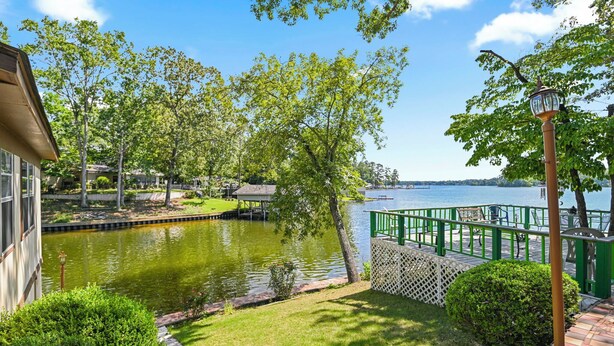 Un tranquillo giardino sul lago con uno stagno, recinzione verde e vista sul lago.