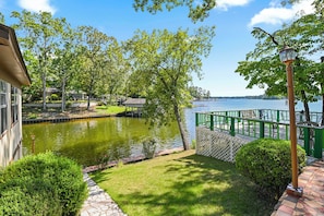 A serene lakeside garden with a pond, green fencing, and a view of the lake. - The Jordan View (Titus)
