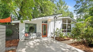A modern house with a covered patio, a dining area with a table and chairs, and a red door. - The Big Chill – 4BR 2.5BA, Sleeps 10, Auburn Retreat Near Downtown & Campus (Auburn)