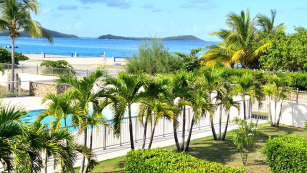 A pool area with palm trees and a view of the ocean. - Luxury Sea-View 2 Bedrooms,  Duplex town house, Pool, private OrientBeach Access (Orient bay)