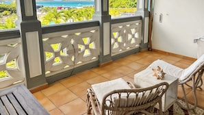 A balcony with wicker furniture, a view of the sea, and a tiled floor. - Luxury Sea-View 2 Bedrooms,  Duplex town house, Pool, private OrientBeach Access (Orient bay)