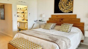A bedroom with a large bed, a wooden headboard, a bedside table, a nightstand, and a wall-mounted artwork. - Luxury Sea-View 2 Bedrooms,  Duplex town house, Pool, private OrientBeach Access (Orient bay)