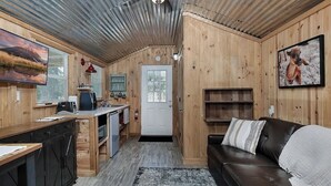 A cozy cabin interior with a kitchen, dining area, and living room. - Pixie's Porch Tiny Home (Centerville)