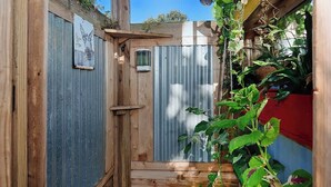 A narrow wooden gate with a corrugated metal door, a small wooden shelf, and a hanging plant. - Pixie's Porch Tiny Home (Centerville)