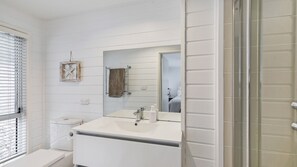 A bathroom with a white vanity, a large mirror, and a towel rack. - Treetops - Family House (AVOCA BEACH)