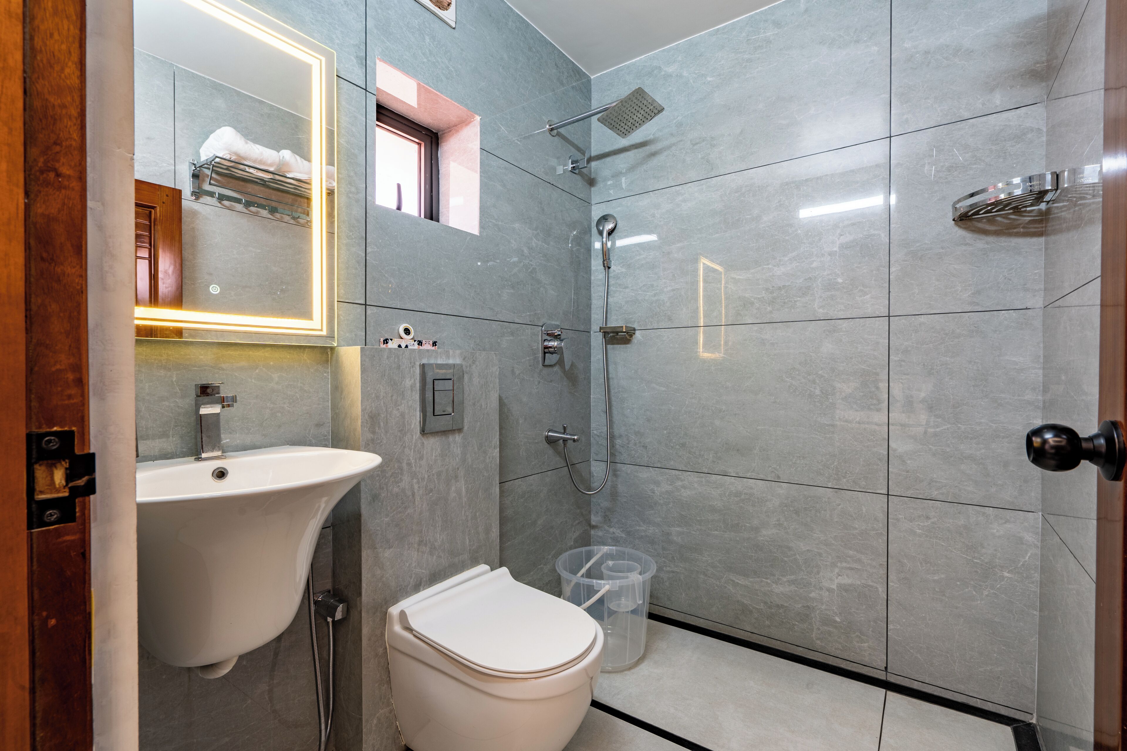 Une salle de bain moderne avec un lavabo, des toilettes et une douche, le tout de couleur blanche.