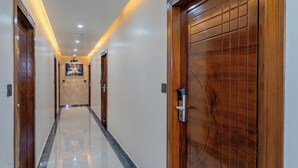 Un pasillo de hotel con puertas de madera, piso de baldosas e iluminación empotrada.