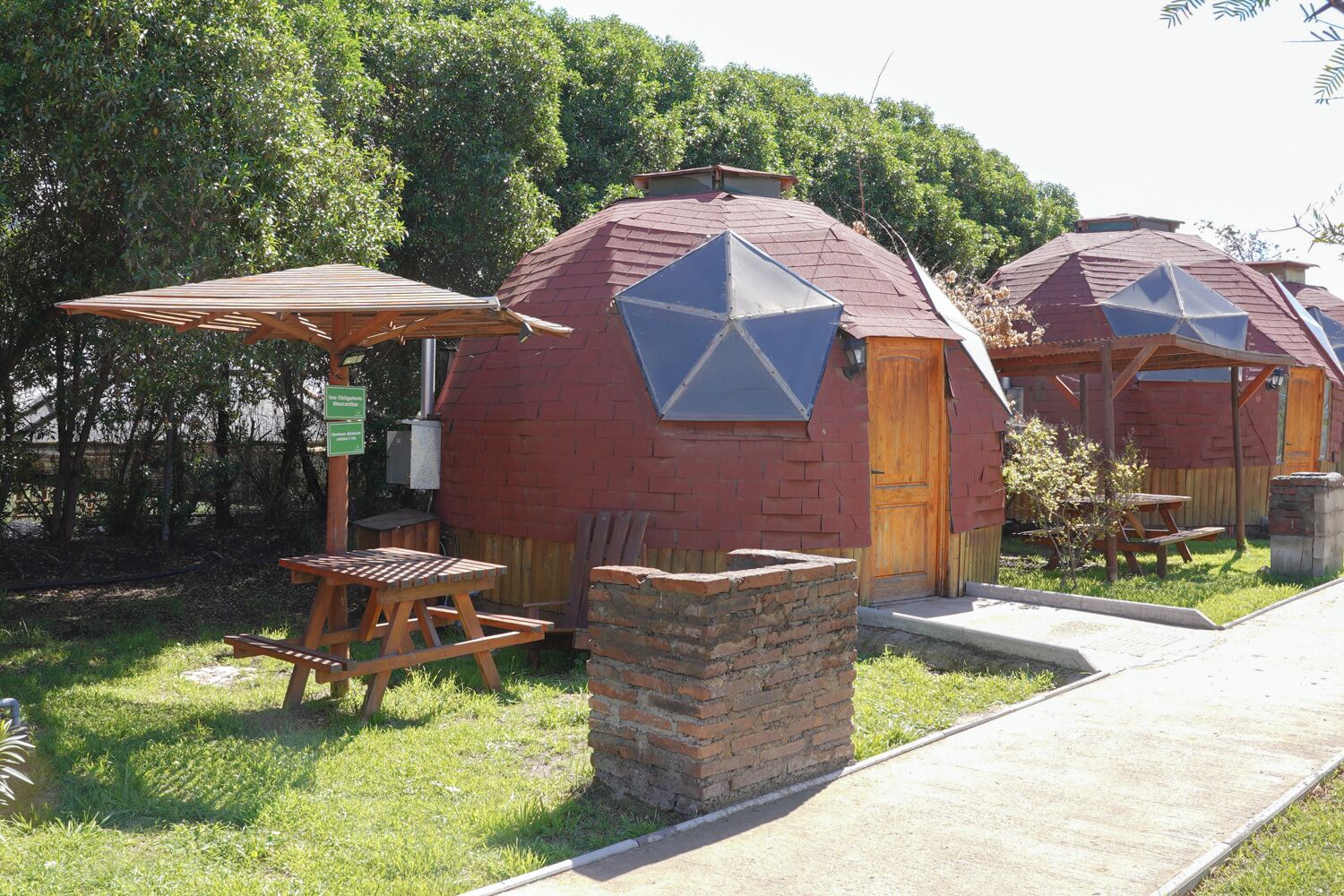 A rustic cabin with a brick exterior, a wooden door, and a picnic table with benches.