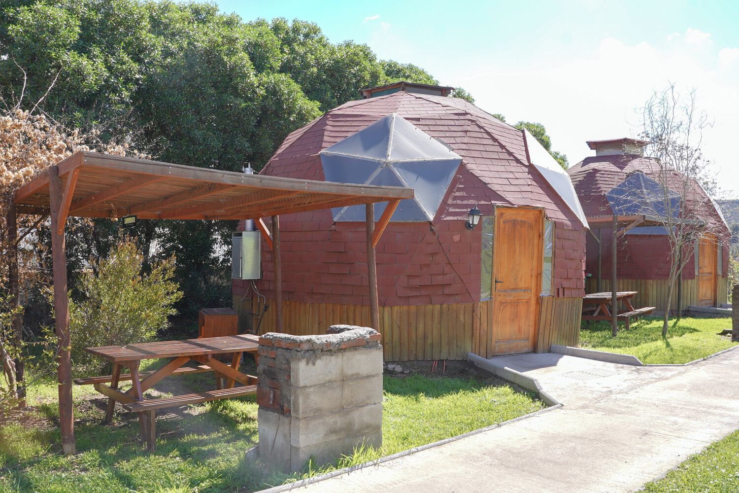 A rustic cabin with a star-shaped window, a wooden pergola, and a picnic table.