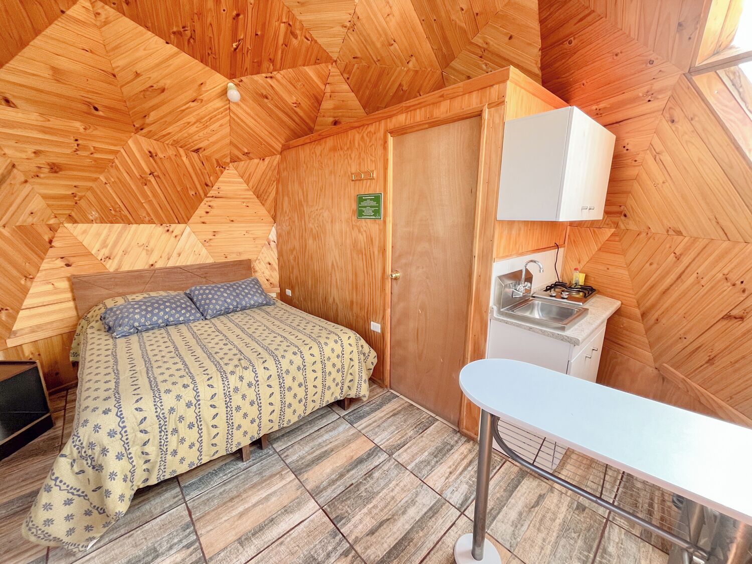 Une pièce de taille modeste comprenant un lit, un petit coin cuisine et un plafond en bois.