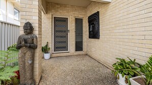 A courtyard with a Buddha statue, a potted plant, and a brick wall. - "Poolside Escape in Scarborough" (Scarborough)